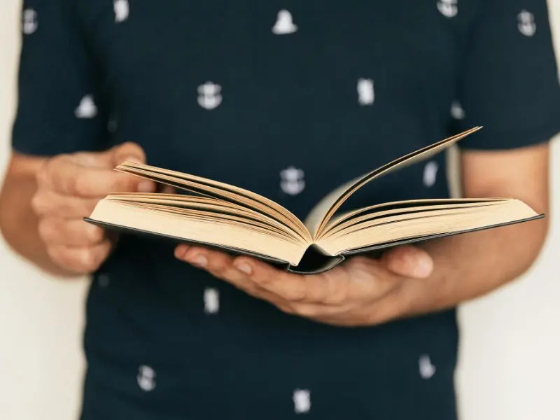 Close-up of a person holding an open book, symbolizing storytelling and shared experiences.