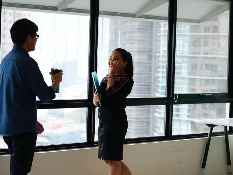 Why do I have trouble speaking when nervous? A professional man and woman talking in an office, with the woman appearing shy, illustrating nervousness in conversation.