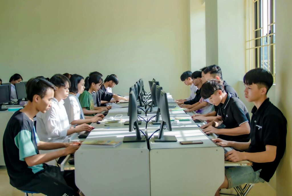 Group of people sitting together but focused on laptops, showing how AI and digital tools impact social skills